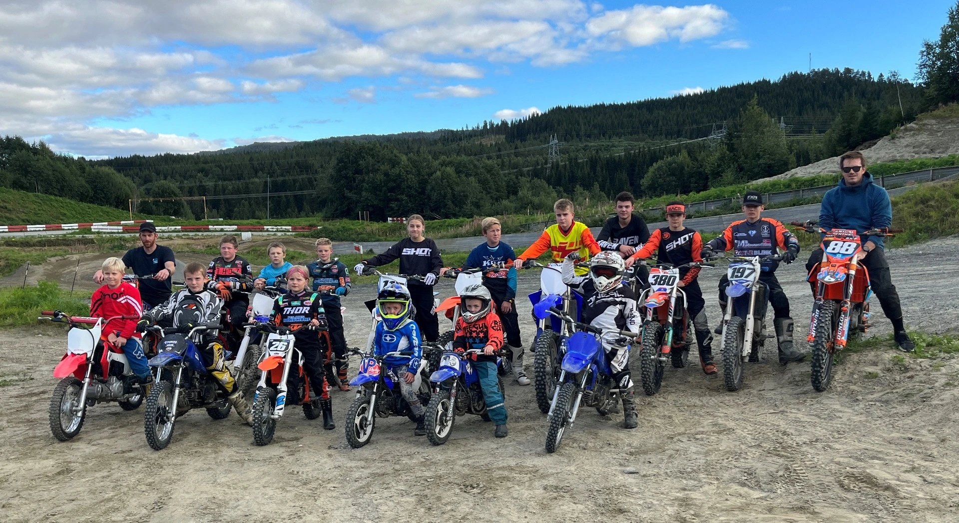 En gruppe står oppstilt med hver sin motorcross, foto