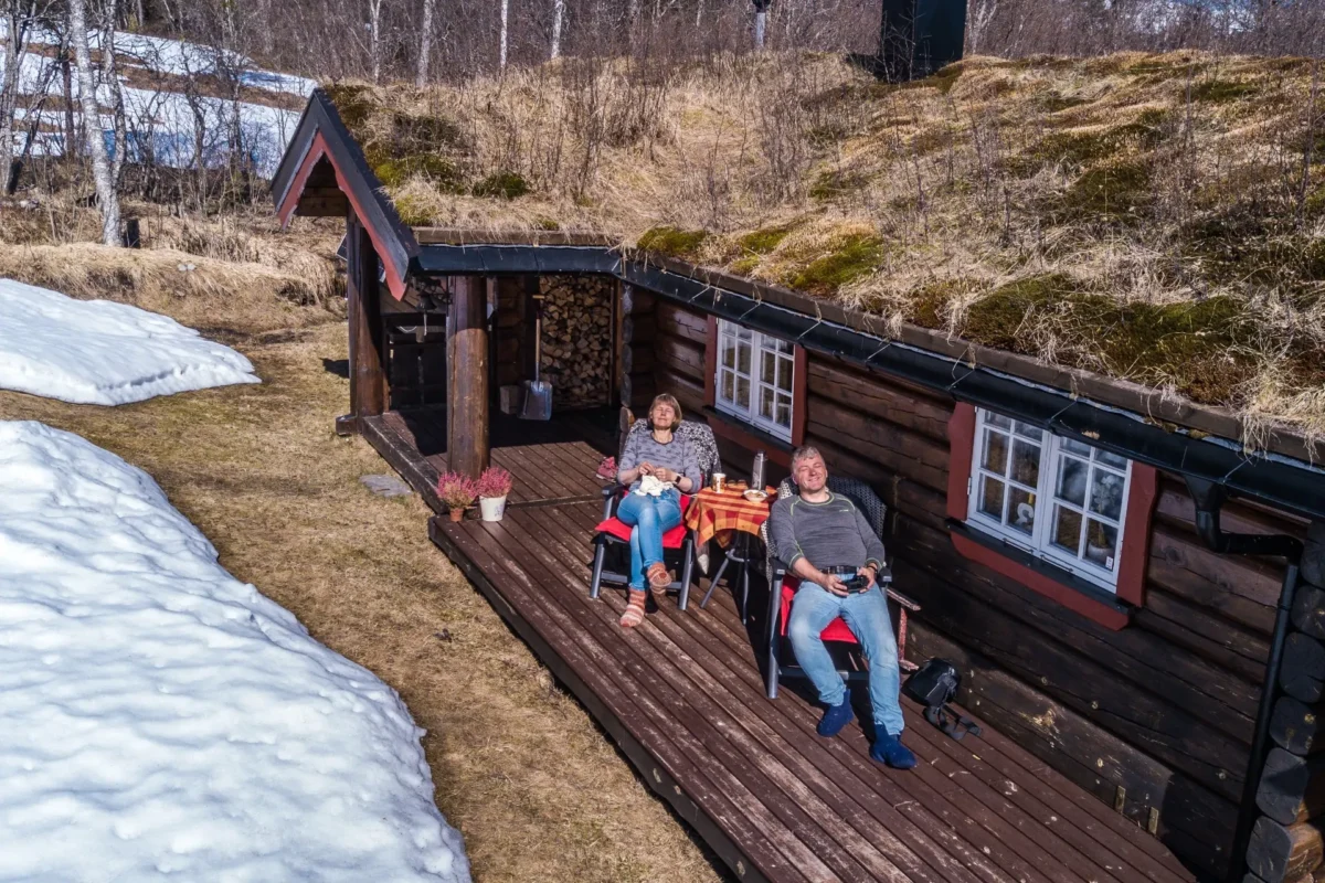 To personer nyter solen på terassen på hytte, foto