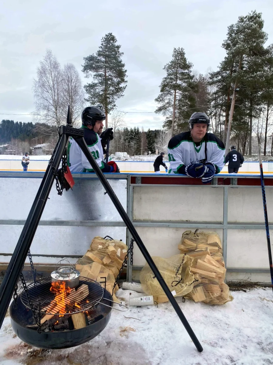 To personer står ved en bålpanne, foto