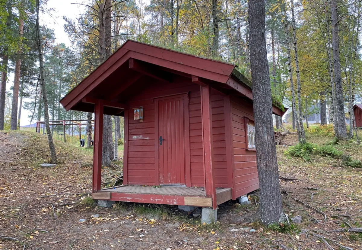 Rødt lekehus med trær rundt, foto