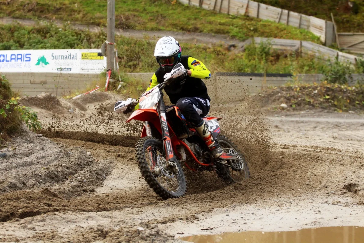 Motorcrossfører i fart rundt en sving, foto