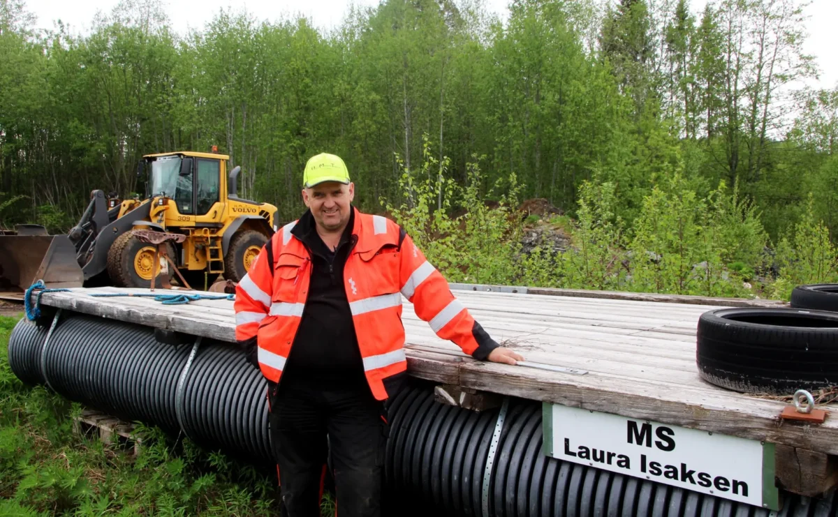 Person står ved en flåte som ligger på land, foto