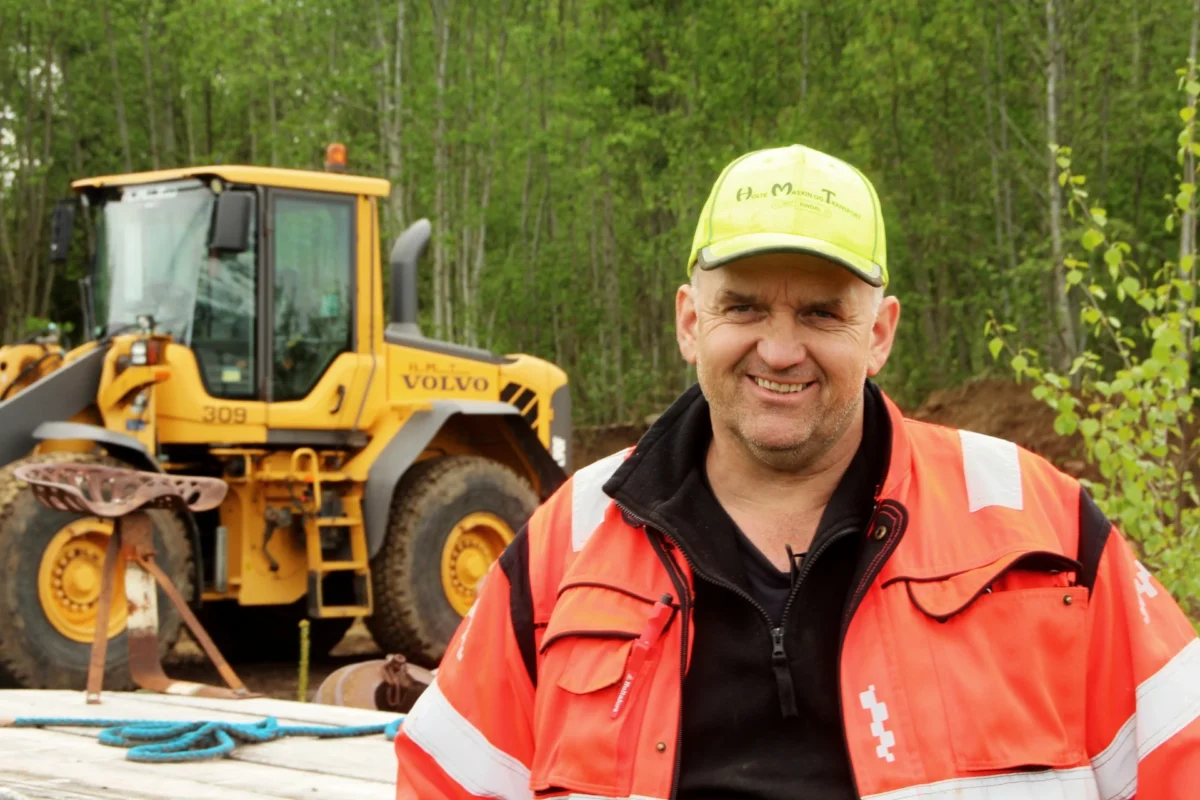 Person i arbeidstøy står foran en hjullaster, foto