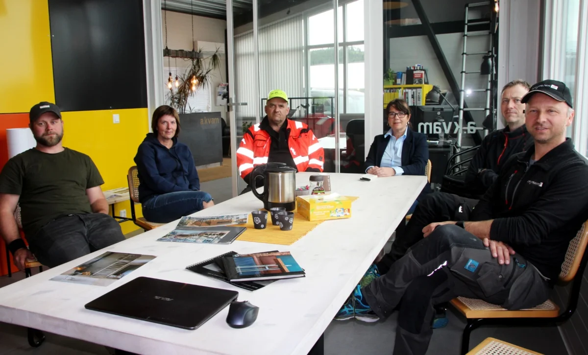 Personer i arbeidstøy sitter rundt et bord, foto