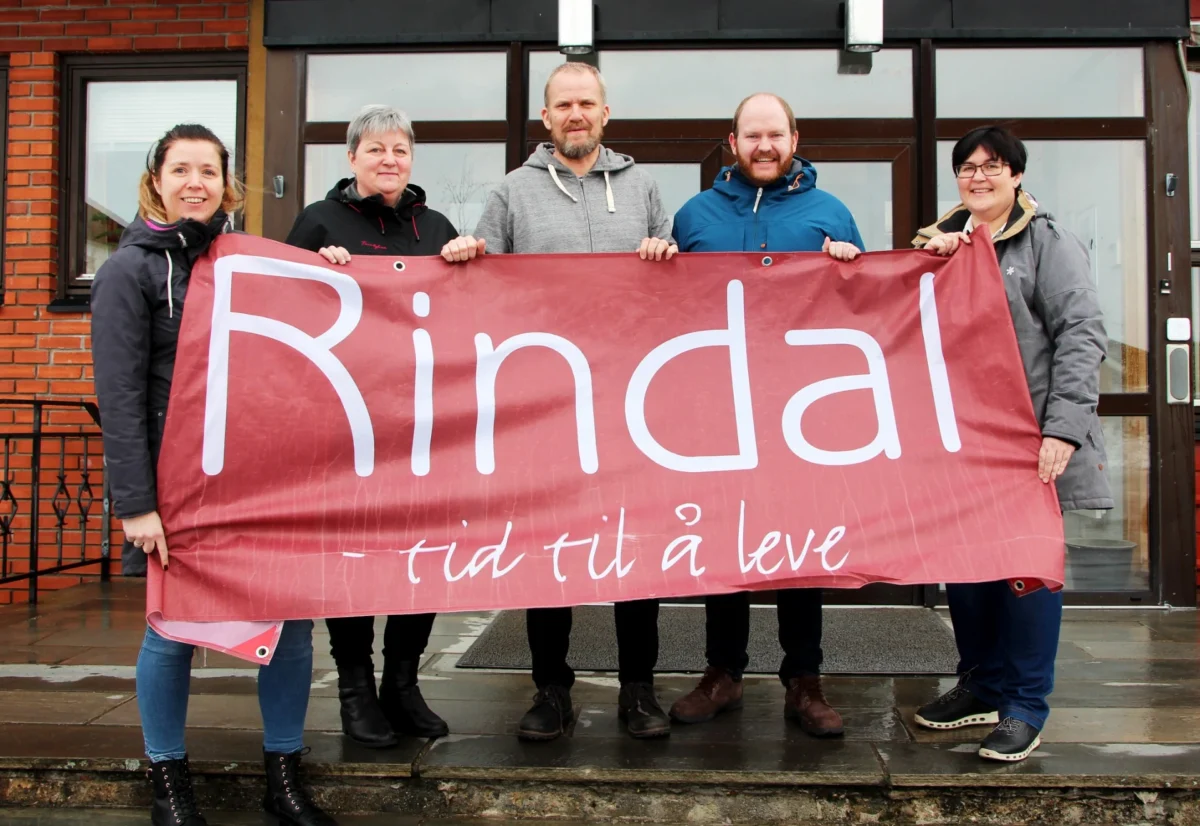 Fem personer holder opp et banner hvor det står "Rindal - tid til å leve", foto