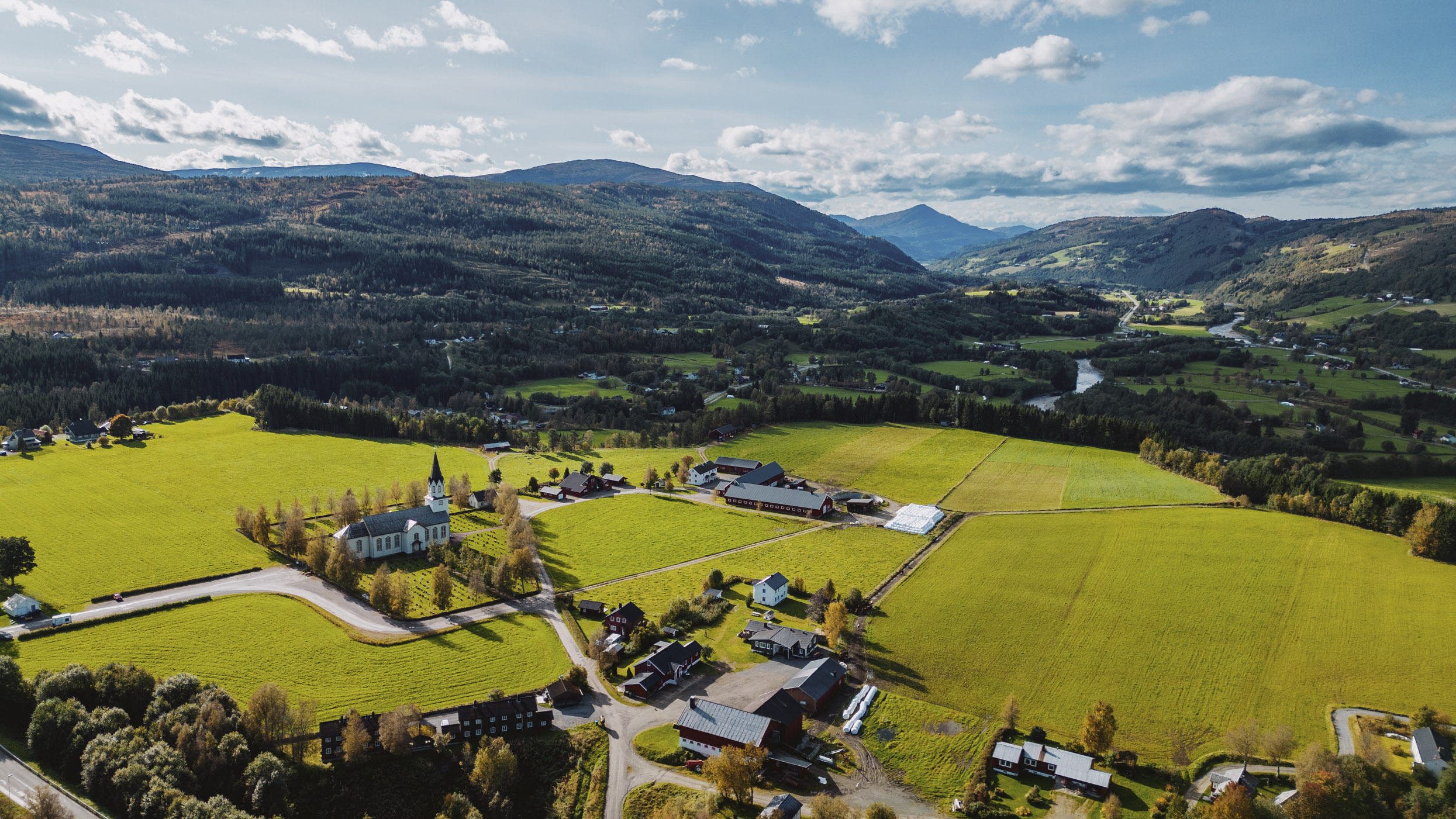 Dronebilde av kirke og landskapet rundt, foto