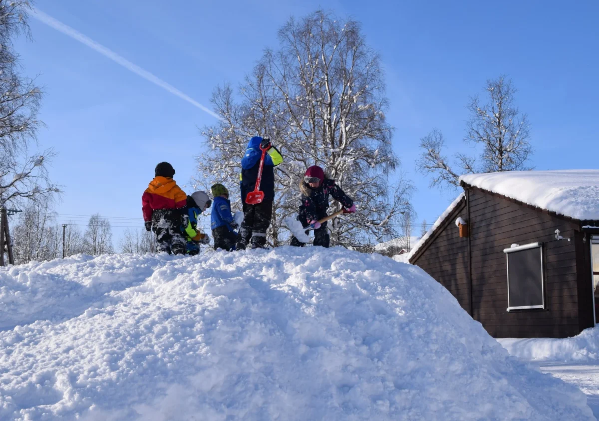 Barnehagebarn graver med spader i snøen, foto