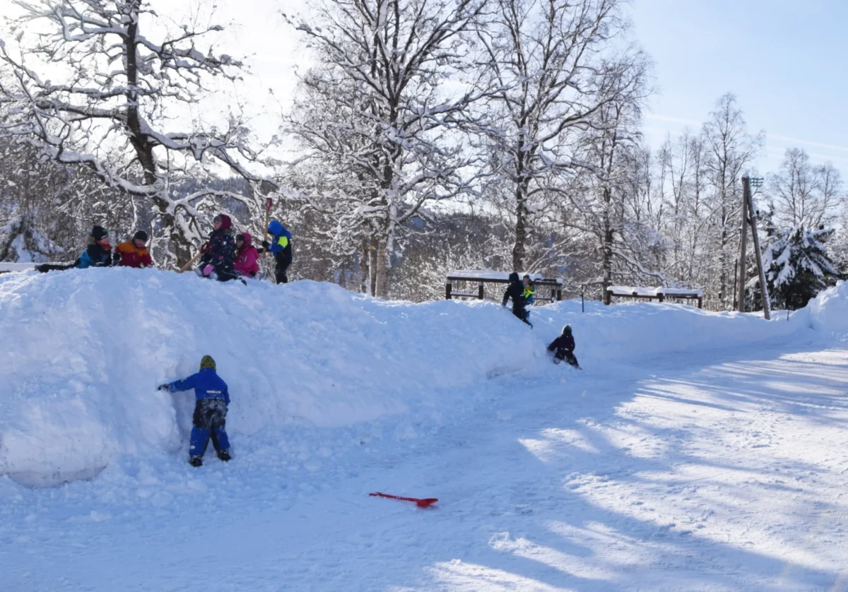 Barnehagebarn leker oppå en stor brøytekant, foto